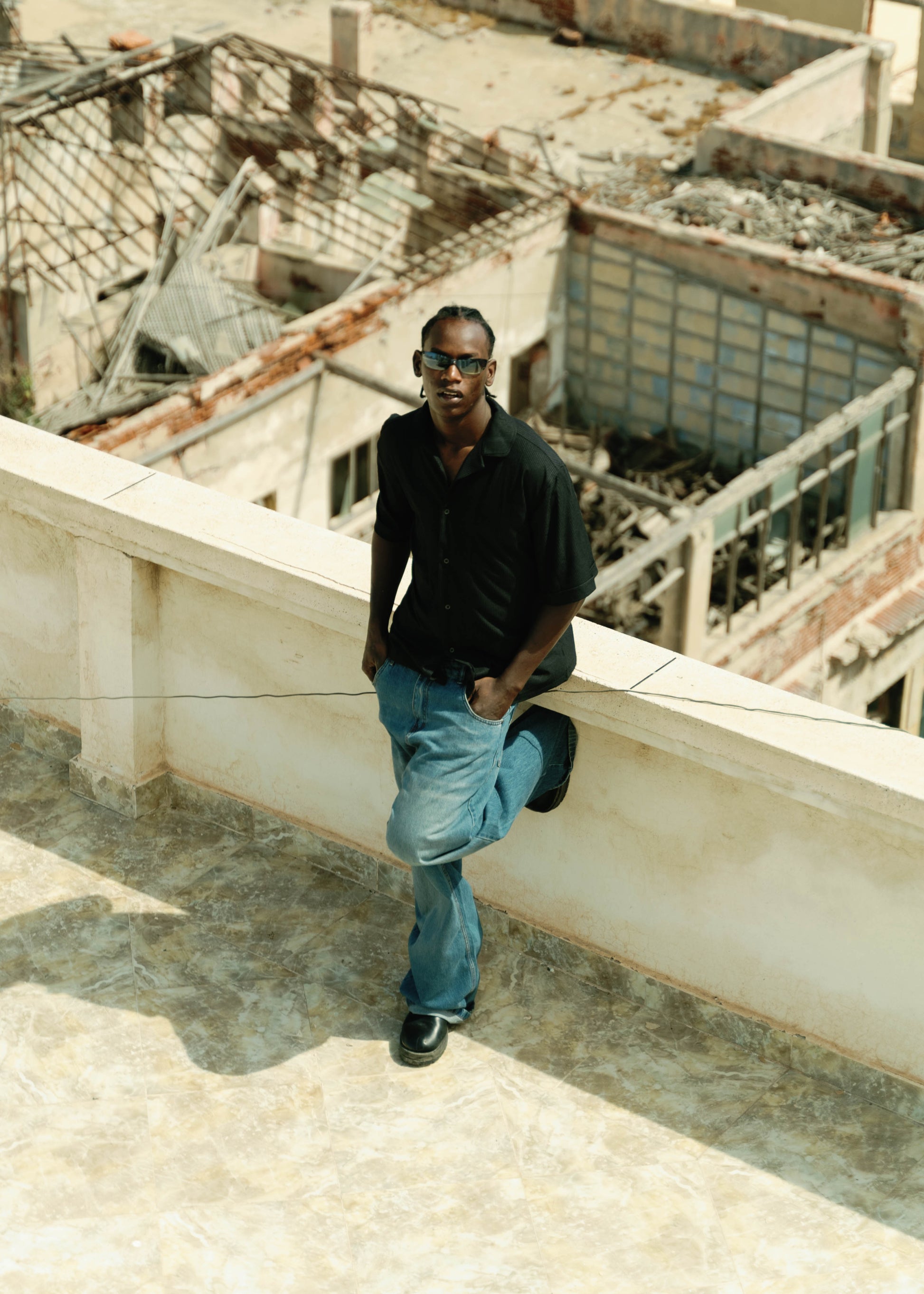 Man standing on a rooftop with urban destruction in the background