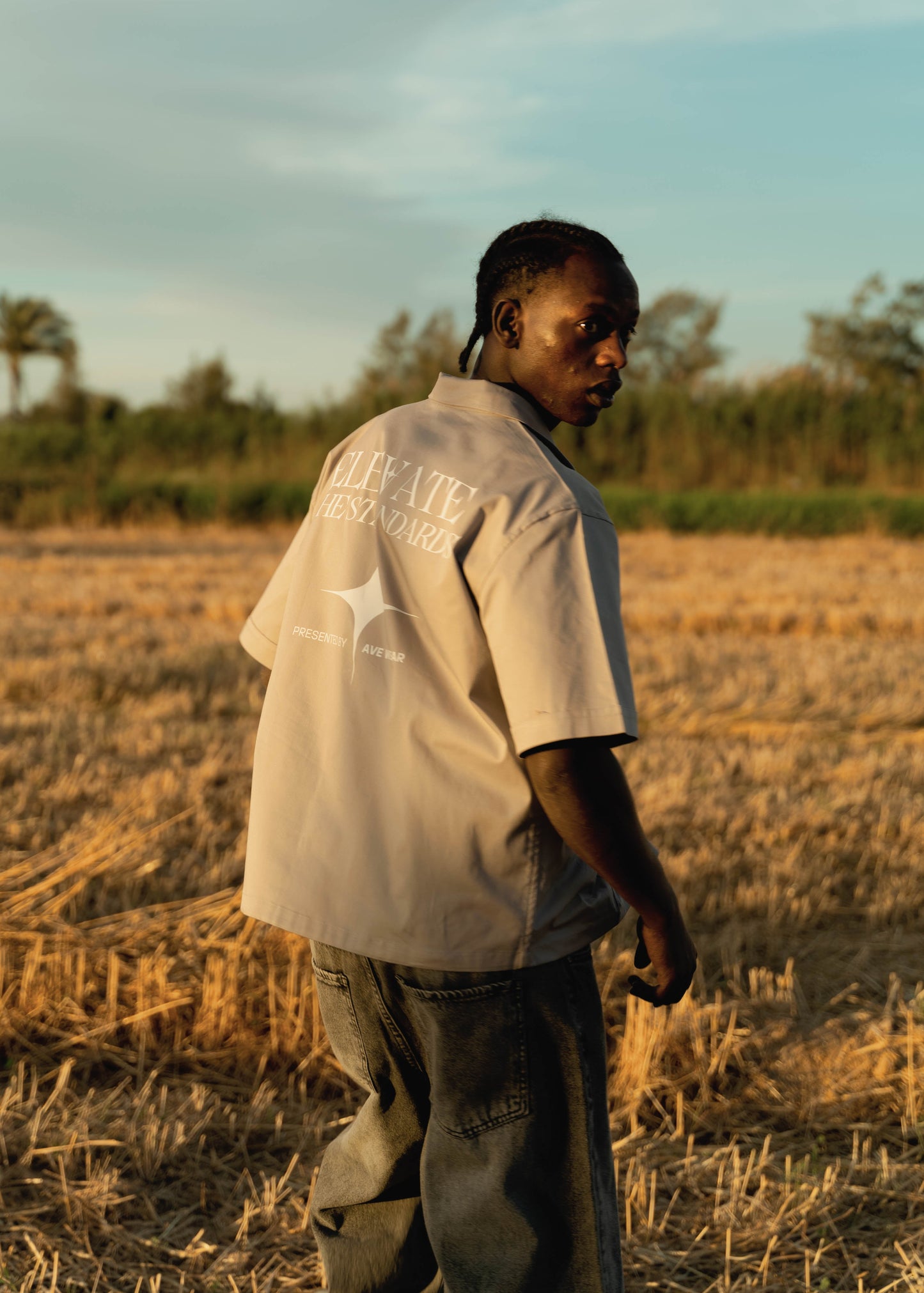 Man standing in a field with trees and sky in the background